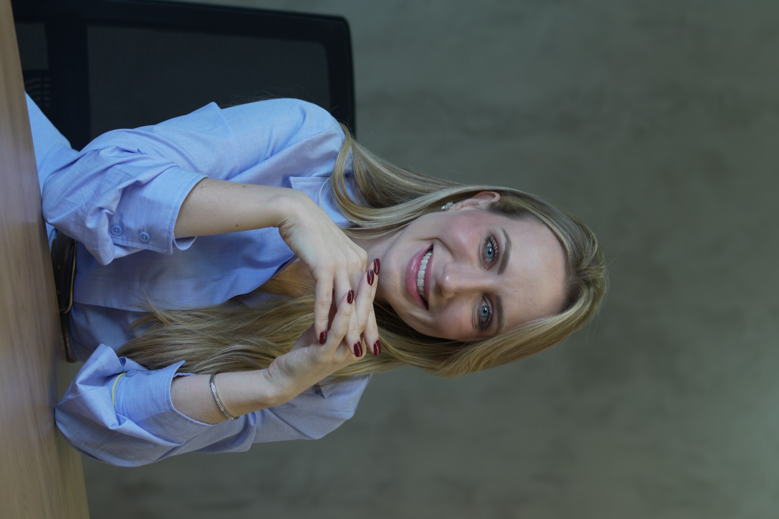 Diretora da Elétrica Paraná sorrindo em sua mesa de trabalho
